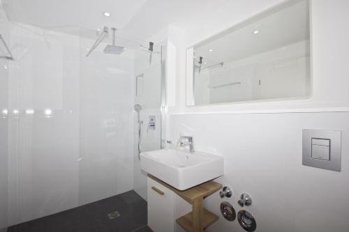 a white bathroom with a sink and a shower at mit Meerblick, gratis Nutzung vom AHOI Erlebnisbad und Sauna in Sellin - Haus Inselblick FeWo MEERrauschen in Groß Zicker