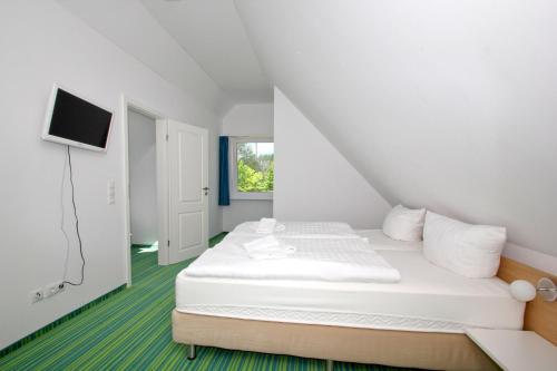 een witte kamer met een bed en een televisie bij strandnahe FeWo mit Balkon, gratis Nutzung vom AHOI Erlebnisbad und Sauna in Sellin - Rex Rugia FeWo 30-5 in Lobbe