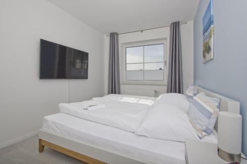a white bed in a room with a window at gratis Nutzung vom AHOI Erlebnisbad und Sauna in Sellin - Haus Inselwind FeWo MEERbodden in Groß Zicker