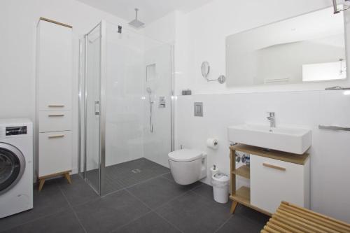 a white bathroom with a toilet and a sink at gratis Nutzung vom AHOI Erlebnisbad und Sauna in Sellin - Haus Inselwind FeWo MEERbodden in Groß Zicker