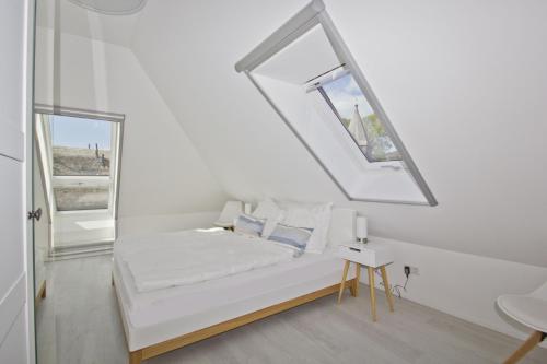 a white room with a bed and a window at Ferienwohnung mit Balkon und Gartennutzung - Haus Inselwind FeWo MEERurlaub in Groß Zicker