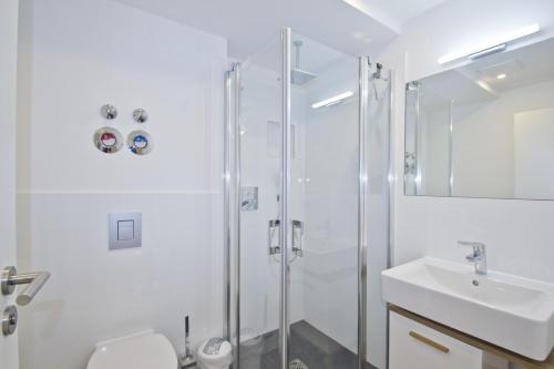 a white bathroom with a shower and a sink at Ferienwohnung mit Balkon und Gartennutzung - Haus Inselwind FeWo MEERurlaub in Groß Zicker
