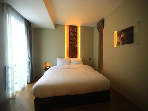a bedroom with a large white bed with a window at Silom One in Bangkok