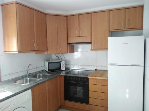 uma cozinha com armários de madeira e um frigorífico branco em Apartamento Rural Casa Paco con Jacuzzi exterior y barbacoa em Aínsa