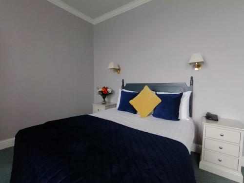 a bedroom with a bed with blue and yellow pillows at Commodore Hotel in Cobh