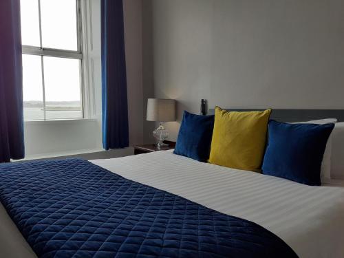 a bedroom with a large bed with blue and yellow pillows at Commodore Hotel in Cobh