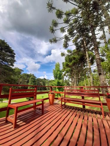 two wooden benches sitting on a wooden deck at Vila Dom Bosco in Campos do Jordão