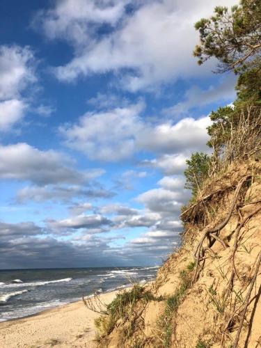 a sandy beach with the ocean and a cloudy sky at Ziemupes Muiža & SPA in Ziemupe
