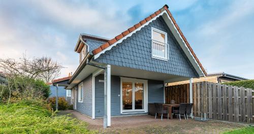 ein blaues Haus mit einem Tisch und einem Zaun in der Unterkunft Appartementanlage am Arnumer See in Hemmingen