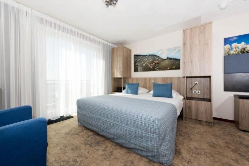 ein Hotelzimmer mit einem Bett und einem TV in der Unterkunft Strandhotel de Vassy in Egmond aan Zee