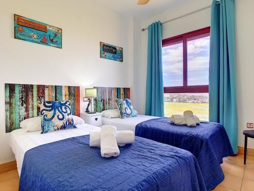 プラヤ・オンダにあるVerdemar 8806 - Resort Choiceの青いカーテンと窓が備わる客室で、ベッド2台が備わります。