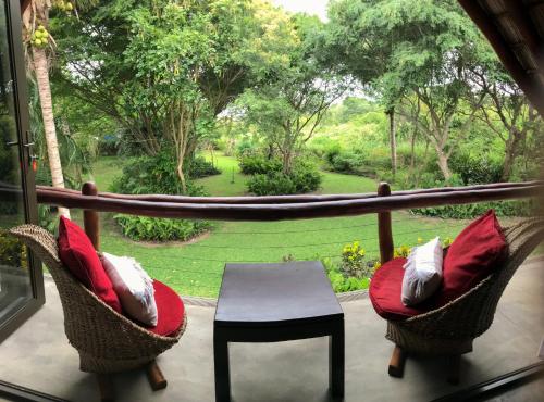 a balcony with chairs and a table and a view of a garden at Casa Jardim in Vilanculos