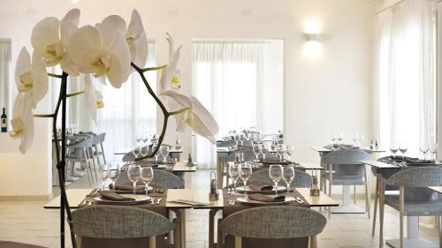 a dining room with tables and chairs and white flowers at Piccolo Hotel - Adults Only in Porto Ottiolu
