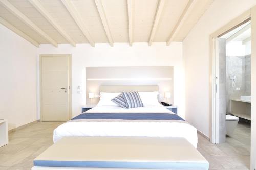 a white bedroom with a bed and a bathroom at Piccolo Hotel - Adults Only in Porto Ottiolu