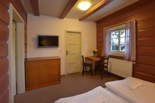 a bedroom with a bed and a desk and a television at Prezidentská in Bedřichov