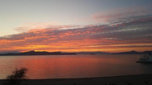 a sunset over a body of water with a boat at Villa Rokanes Glass Stone with Pool in Kouvéllai