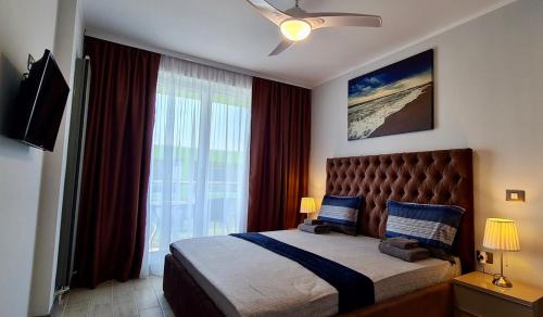 ein Schlafzimmer mit einem Bett und einem großen Fenster in der Unterkunft Sensation Alezzi Apartment Resort in Mamaia Nord – Năvodari