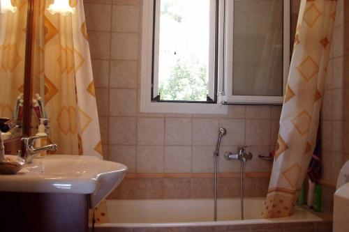 a bathroom with a tub and a sink and a window at Cephalonia Sami, luxury apartment. in Sami