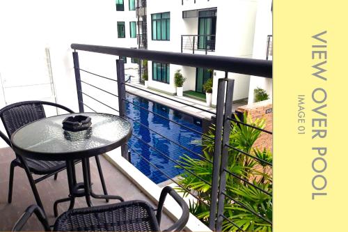 a table and chairs on a balcony with a pool at Stylish Condo w. Pool View 2F in Kamala Beach