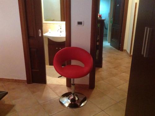 a red chair in a bathroom with a sink at La Vecchia Taverna B&B in Prignano Cilento