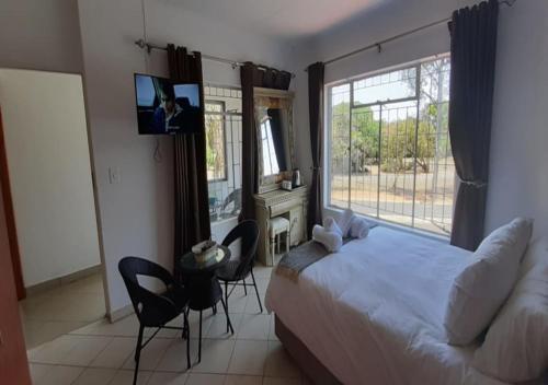 ラステンバーグにあるBetter Life Guesthouseのベッドルーム1室(ベッド1台、椅子、窓付)