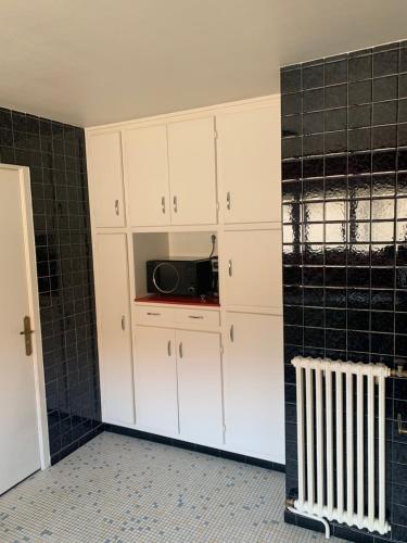 a kitchen with white cabinets and a microwave at L’ÉMERAUDE 4 in Chalons en Champagne
