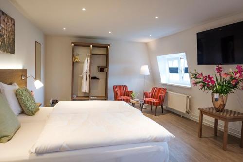 1 dormitorio con 1 cama blanca y 2 sillas rojas en Valuas, en Venlo