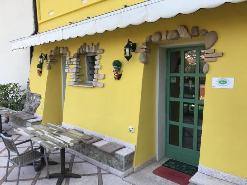 a yellow house with a table and a green door at Borgo Piccolo in Cavaion Veronese