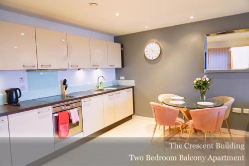 a kitchen with a table and a clock on the wall at Gunwharf Quays Apartments in Portsmouth