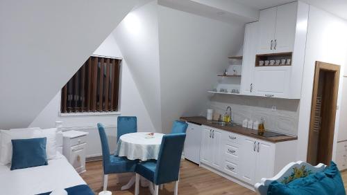 a kitchen with a table and blue chairs in a room at Vila ZLATARSKA PAHULJA --- apartman " BELE NOĆI " in Nova Varoš