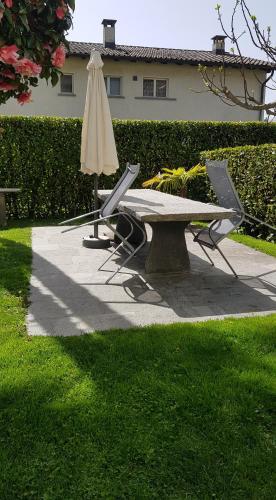 a picnic table with an umbrella and two chairs at New "Casa Maria" in Ascona