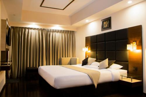 a hotel room with a large bed and a window at Alpine Continental in Shillong
