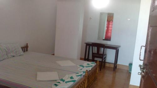 1 dormitorio con cama, mesa y espejo en Stay Well Ayurvedic Beach Resort, en Kovalam