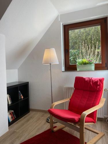 a red chair in a living room with a window at Ferienhof Kröger in Bielefeld