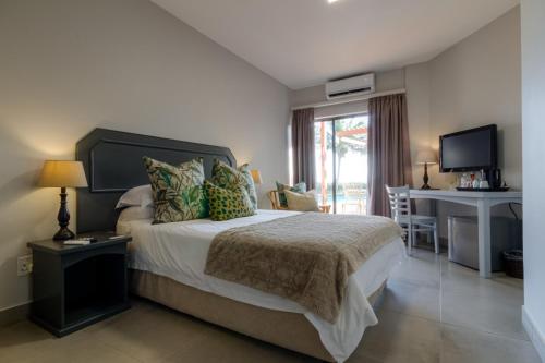 a bedroom with a bed with a desk and a computer at The Ridge Guesthouse in Richards Bay