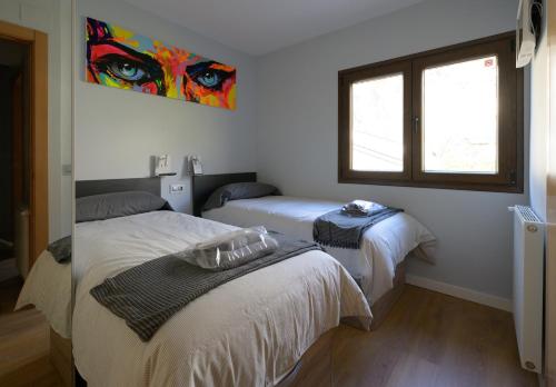 a bedroom with two beds and a window and a painting at Apartamento frente telecabina Vallnord - Bike park 641 in La Massana