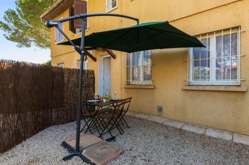 une table avec un parasol vert devant un bâtiment dans l'établissement Studio Varélia - Welkeys, à Six-Fours-les-Plages