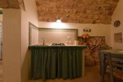 a kitchen with a green curtain next to a sink at Trulli La Zisa in Fasano