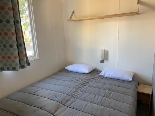 a bed with two pillows in a room with a window at Mobil Home Canet plage in Canet-en-Roussillon