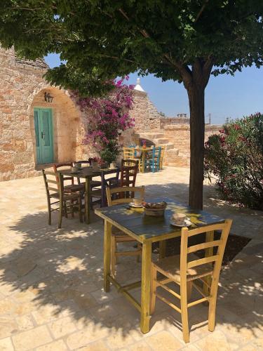 a wooden table and chairs under a tree at Trulli La Zisa in Fasano