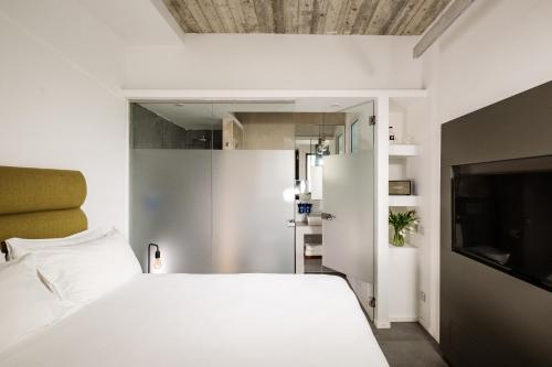 a bedroom with a white bed and a flat screen tv at 19 ROOMS in Valletta