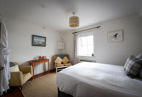 sypialnia z łóżkiem, krzesłem i oknem w obiekcie The Herons Rest Boutique Accommodation w Galway