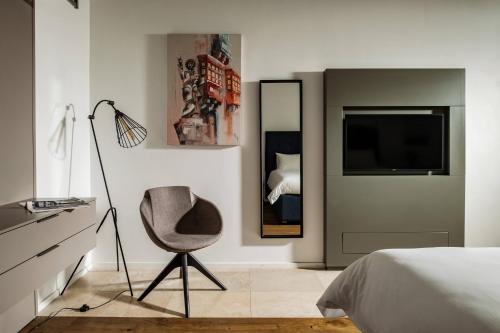 a bedroom with a chair and a tv and a bed at 19 ROOMS in Valletta