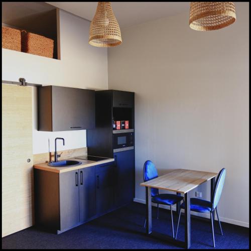 a kitchen with a wooden table and blue chairs at LeDeN in Lissieu