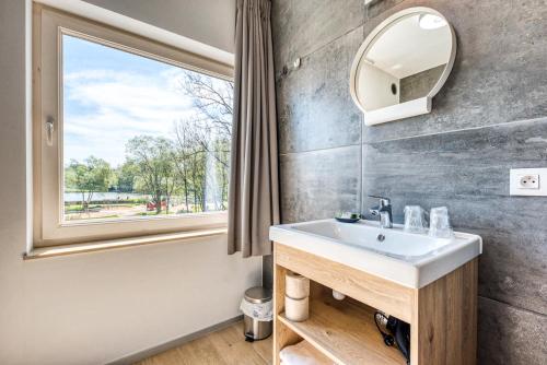 baño con lavabo y ventana en HOTEL L'AVENUE, en Libramont