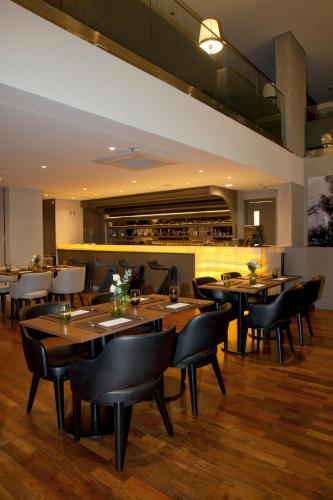 a restaurant with wooden tables and black chairs at NH Collection Curitiba in Curitiba