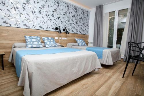 a hotel room with two beds with blue pillows at Hostal Castilla II Puerta del Sol in Madrid