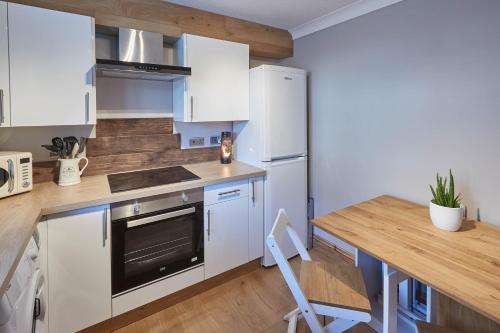 a kitchen with white cabinets and a wooden table at Host & Stay - Amber Shores in Saltburn-by-the-Sea