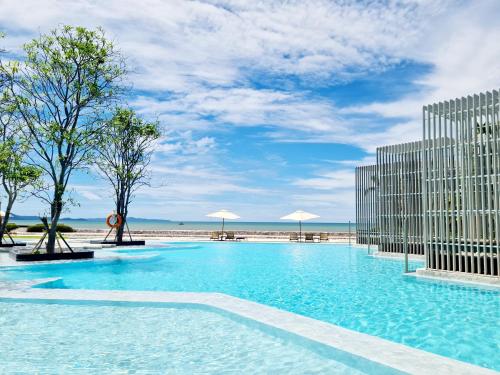 a large swimming pool next to a beach at Veranda Residence pattaya By Sea in Jomtien Beach