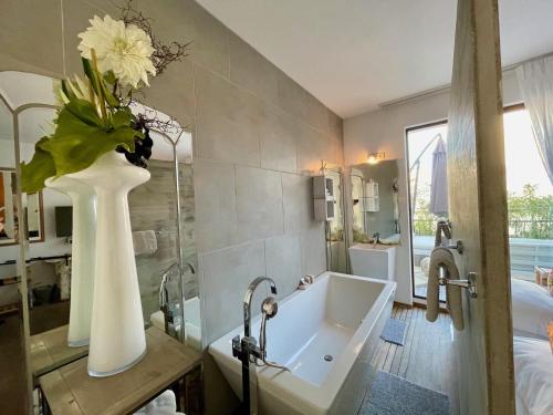 a bathroom with a tub and a vase with flowers in it at Maison De Mon Père in Aigues-Mortes